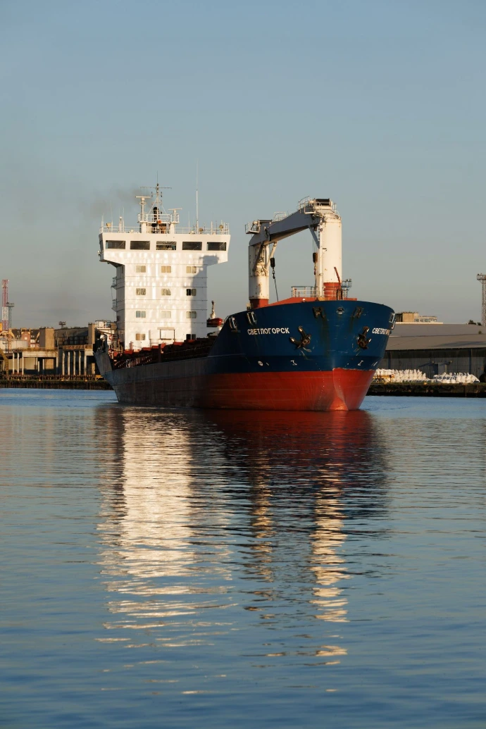A cargo ship sails on calm water.